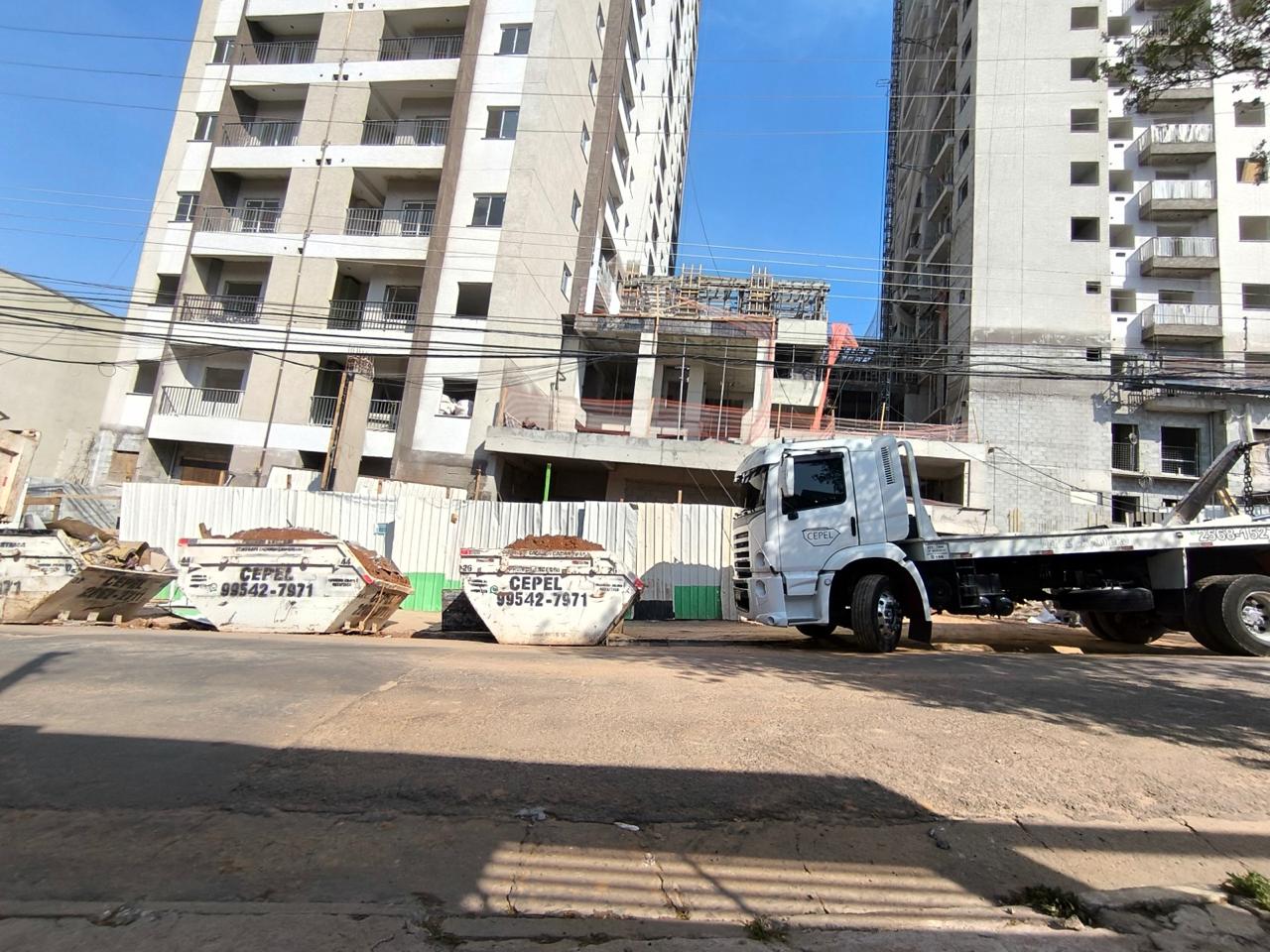 Caminhão e caçambas CEPEL em frente a uma obra
